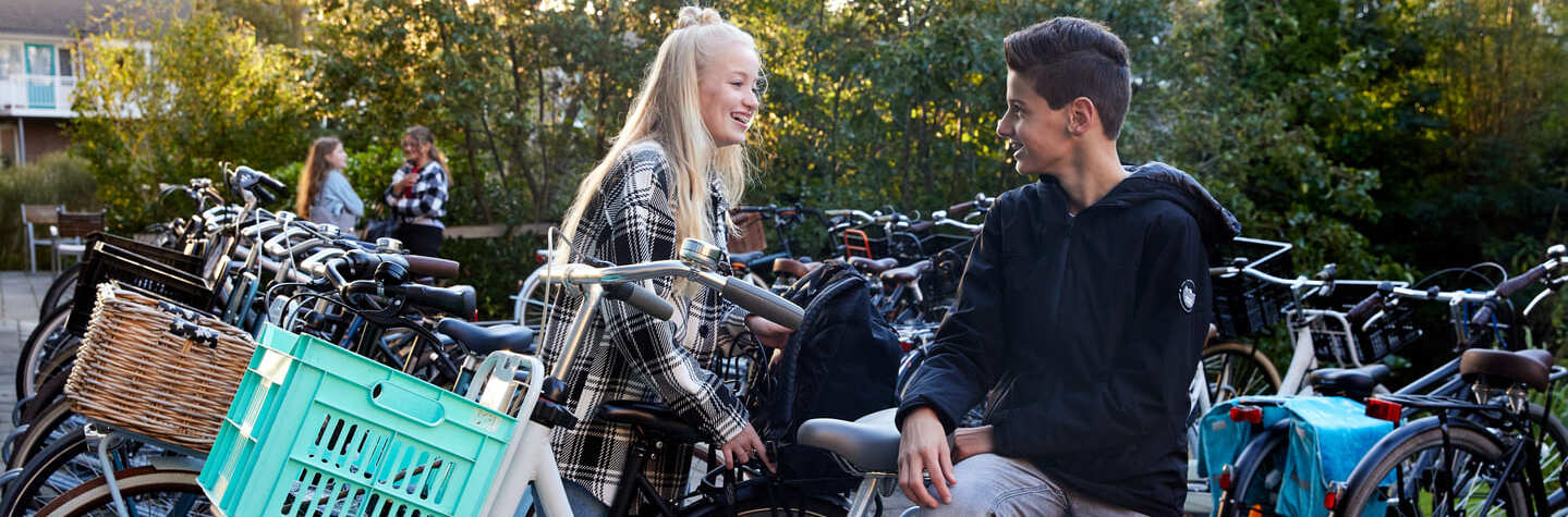 Decoratieve foto van een jongen en een meisje die bij hun fietsen met elkaar aan het praten zijn