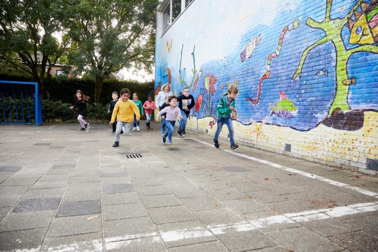 Decoratieve foto van leerlingen die actief zijn op het schoolplein. Ze zijn aan het rennen.