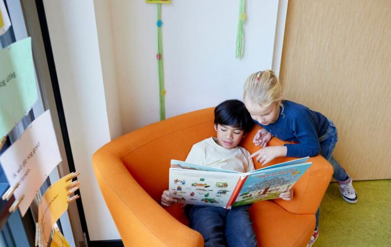 Twee kinderen lezen boek in rustig hoekje op school